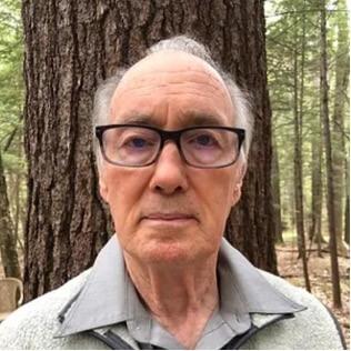 Bob Leverett in the woods in front of a large tree