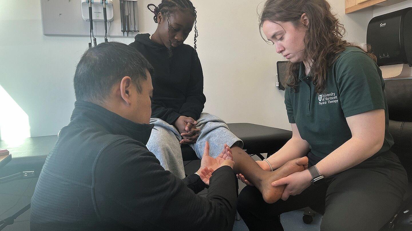 Dr. Reuben Escorpizo and DPT student volunteer Katie Richards meet with a patient at the Winooski school-based health center.