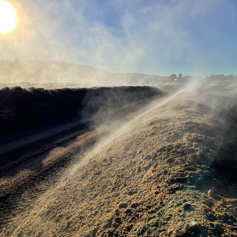 Rows of steaming soil in a farm field on a sunny day
