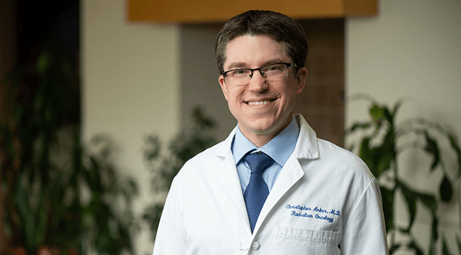a man in a white coat smiling