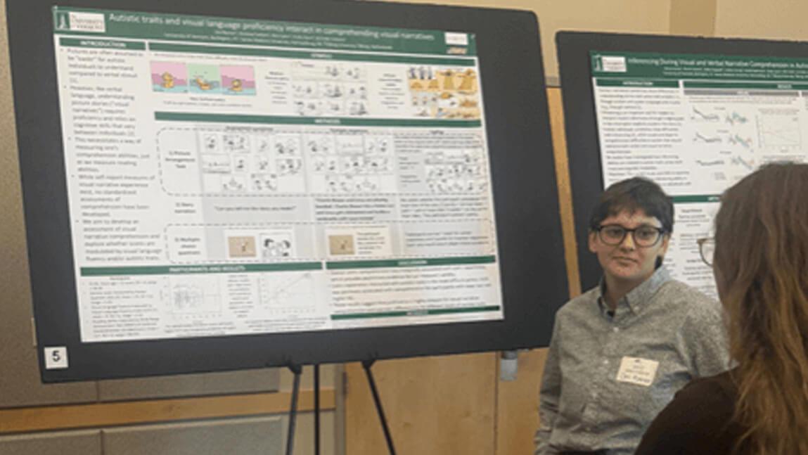 Del Rosner stands in front of a scientific poster engaged with another individual visiting the poster.