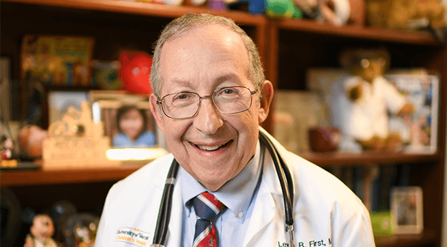 a man in a white coat smiling