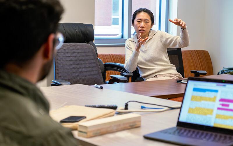 Physics assistant professor Haicen Yue discusses a research publication with her graduate students