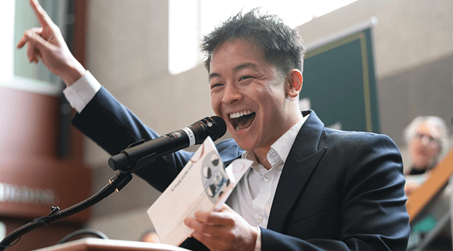 a man celebrating at a podium, holding a letter