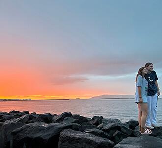 two students by the water at sunset