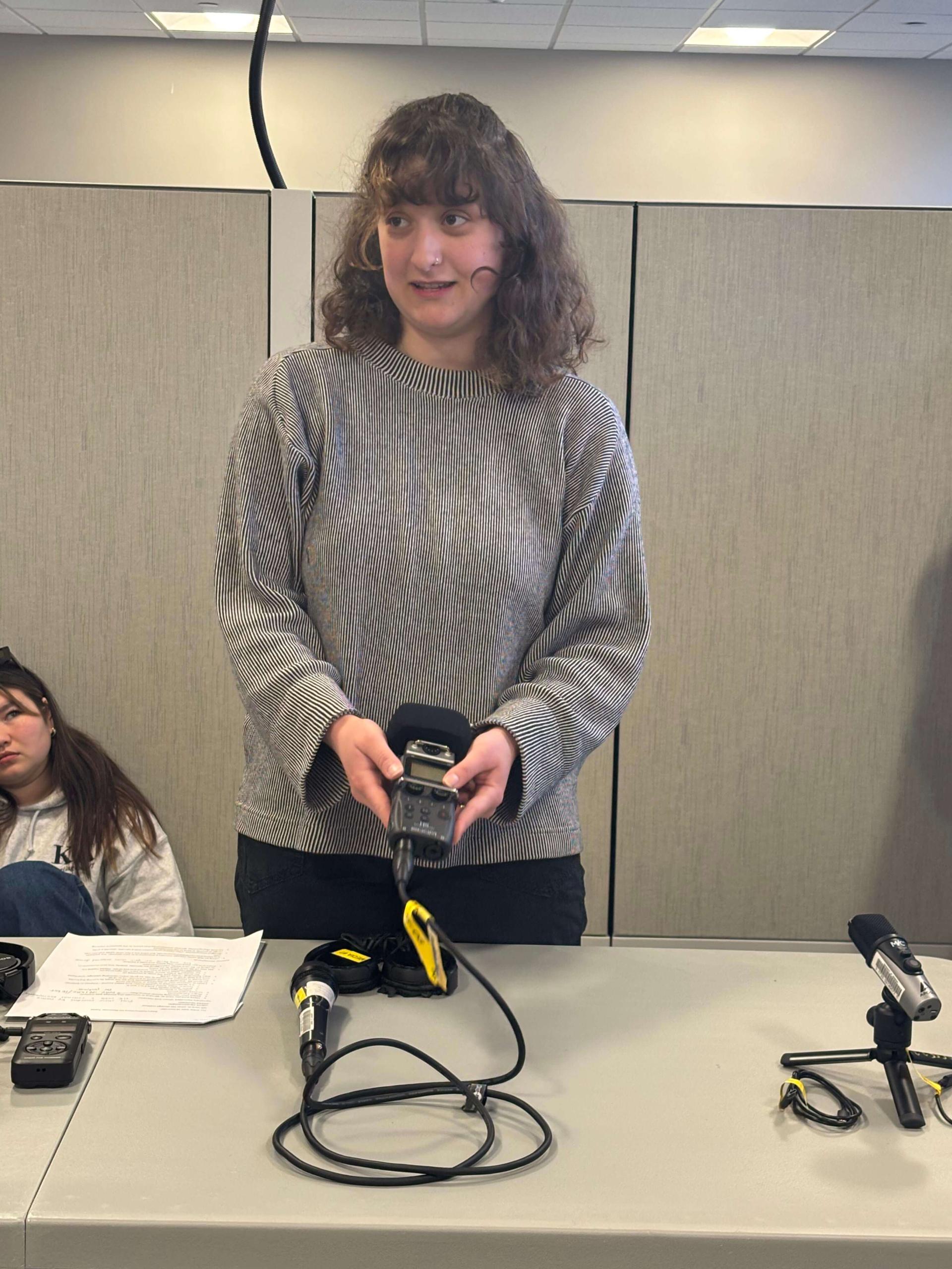 Clemma shows podcasting equipment to an audience.