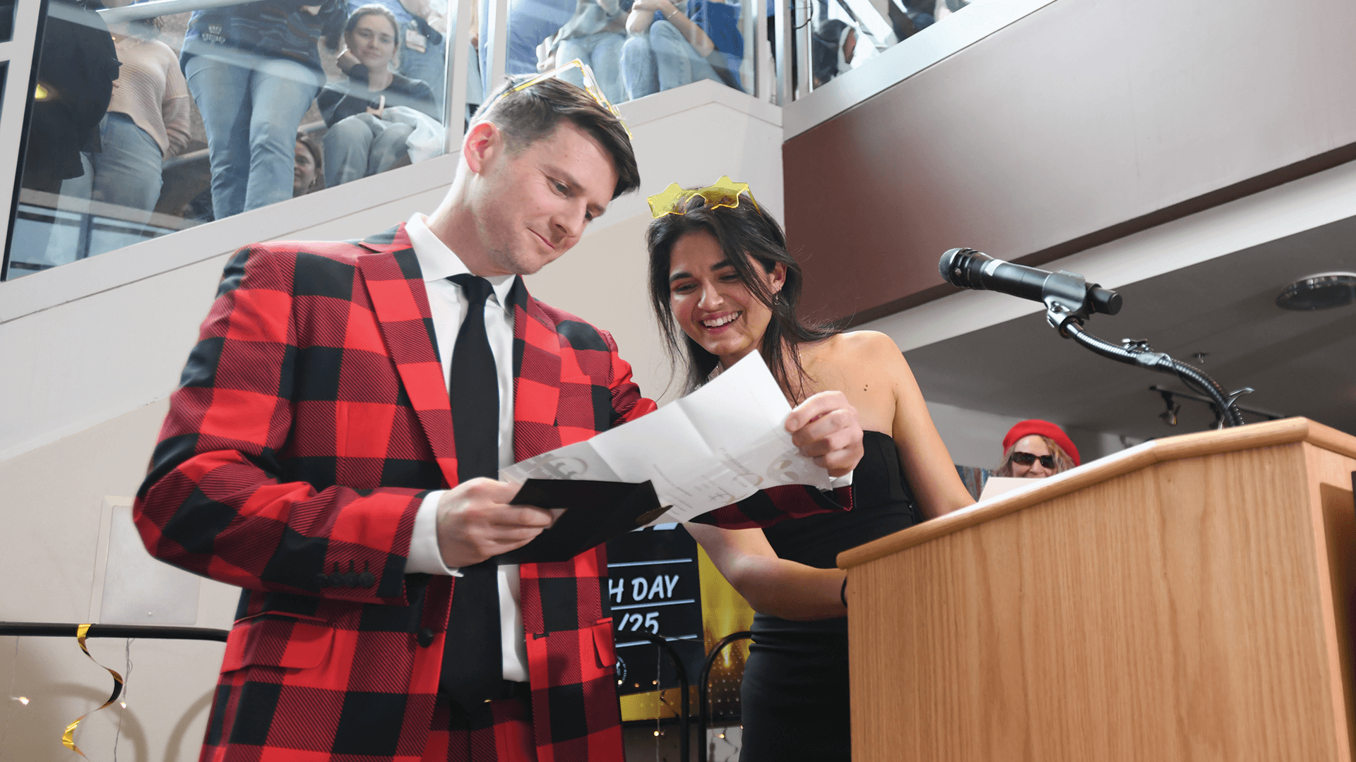 a man and a woman standing at a podium looking at a letter