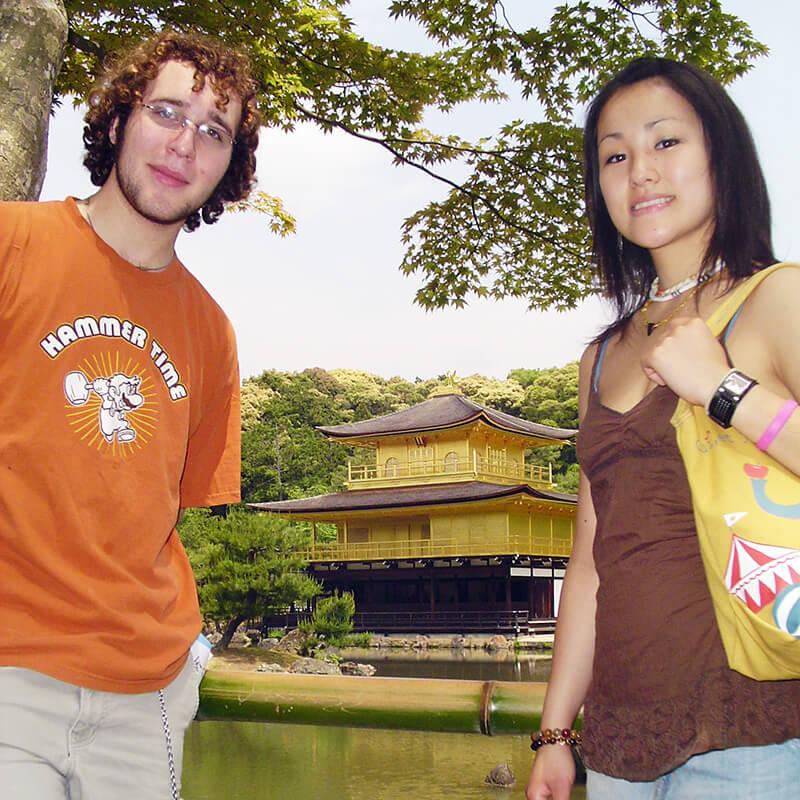 Two people stand by a pond, enjoying the natural beauty and calm surroundings of the landscape