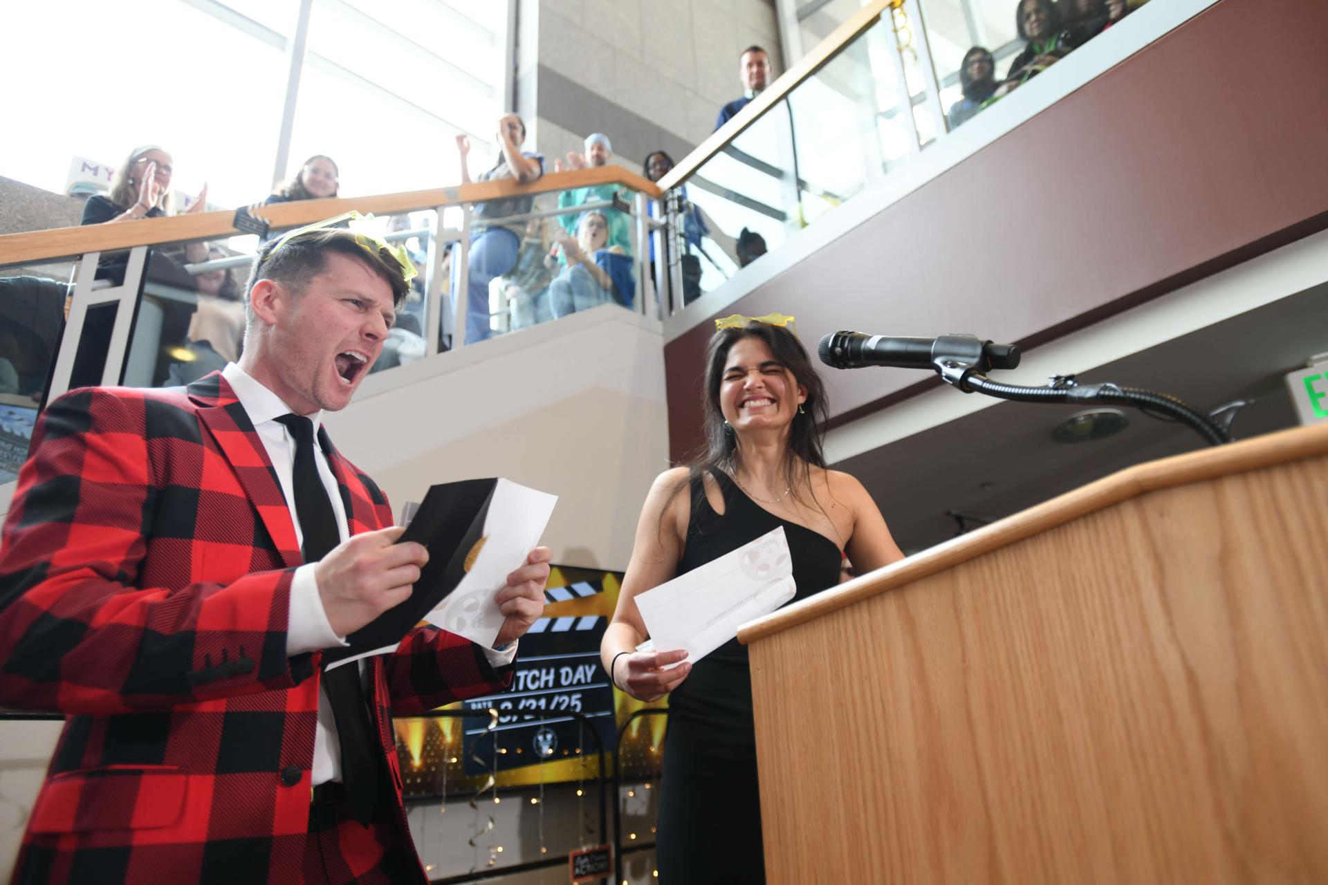 Two people holding envelopes, with excited looks on their faces
