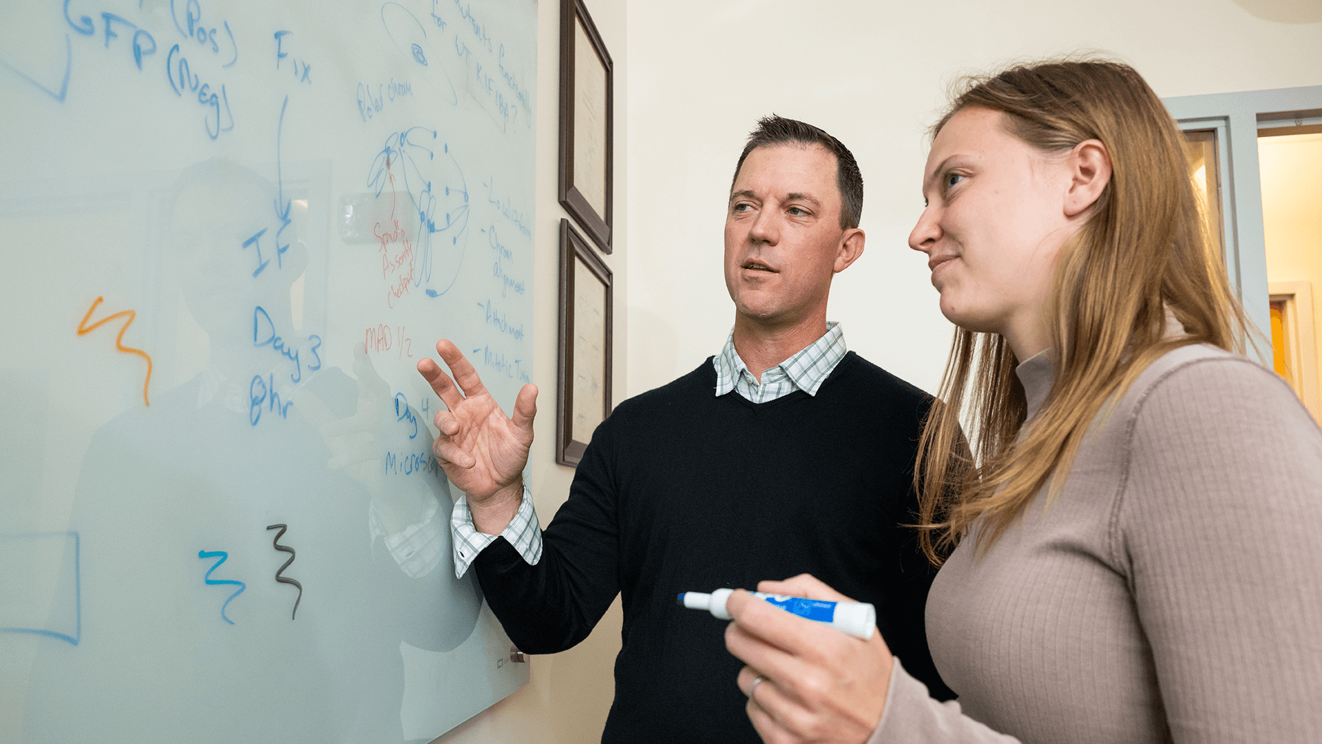 a man and a woman standing at a chalkboard