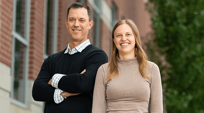 a man and a woman standing outside a building on the UVM campus