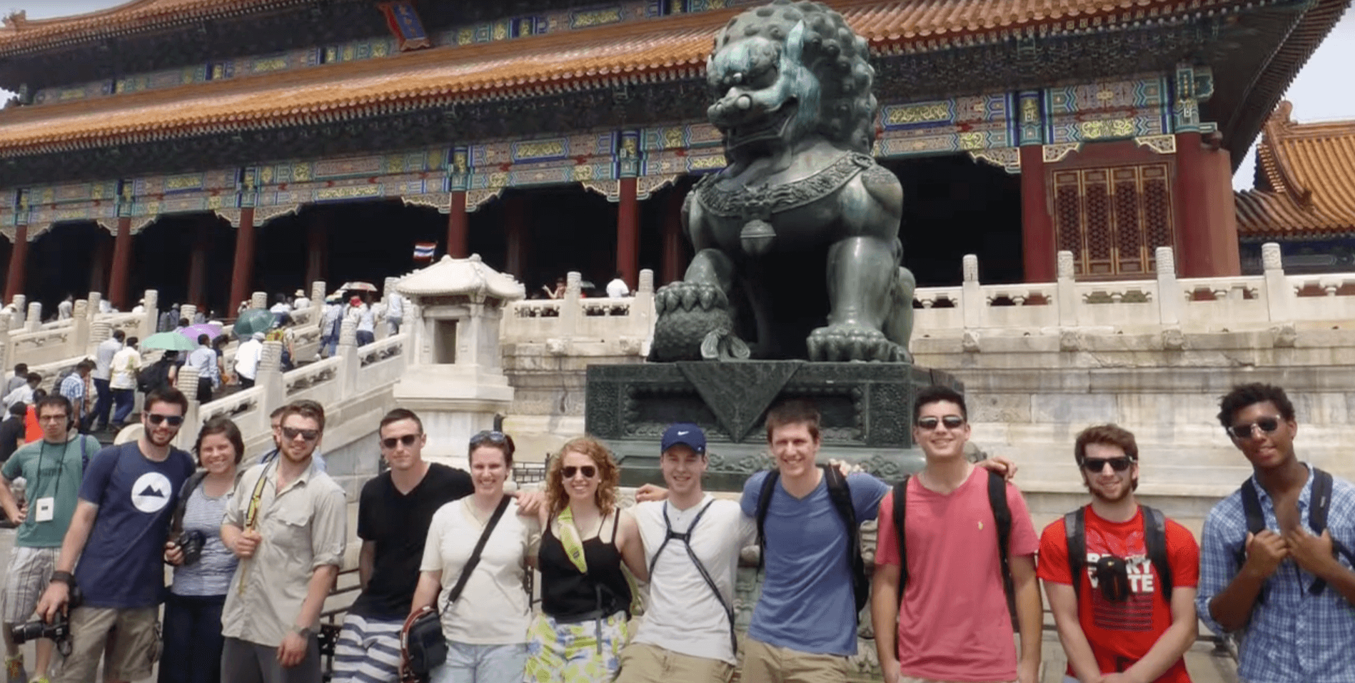 A diverse group of individuals smiling and posing together in front of a large building