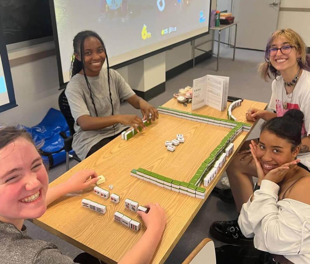 Four students playing mahjong big cube board game