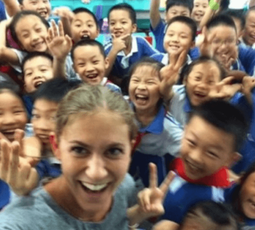 A woman and children smile together in a school 