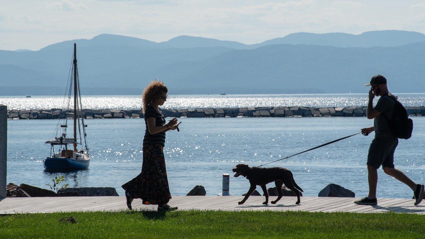 Two people and a dog walking along Burlington waterfront