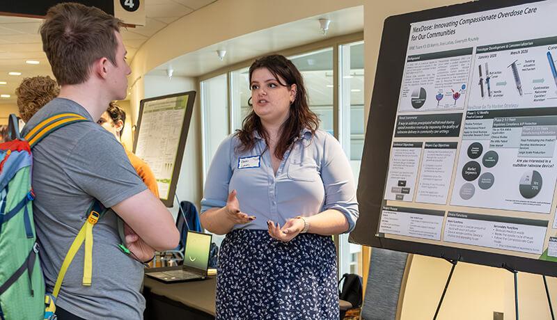 BME senior Arai Lubas shares her team's project, "NexDose Solutions," with visitor to Engineering Design Night.