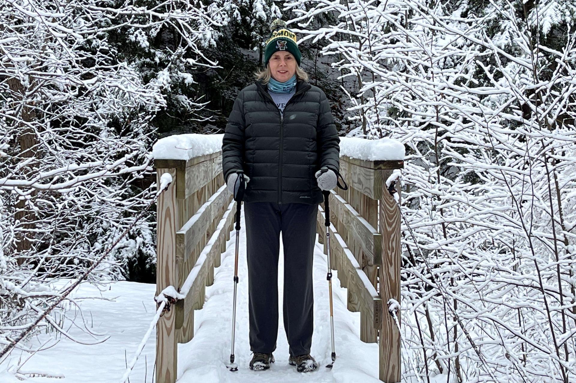 Corinne Thompson hikes across a snow covered bridge