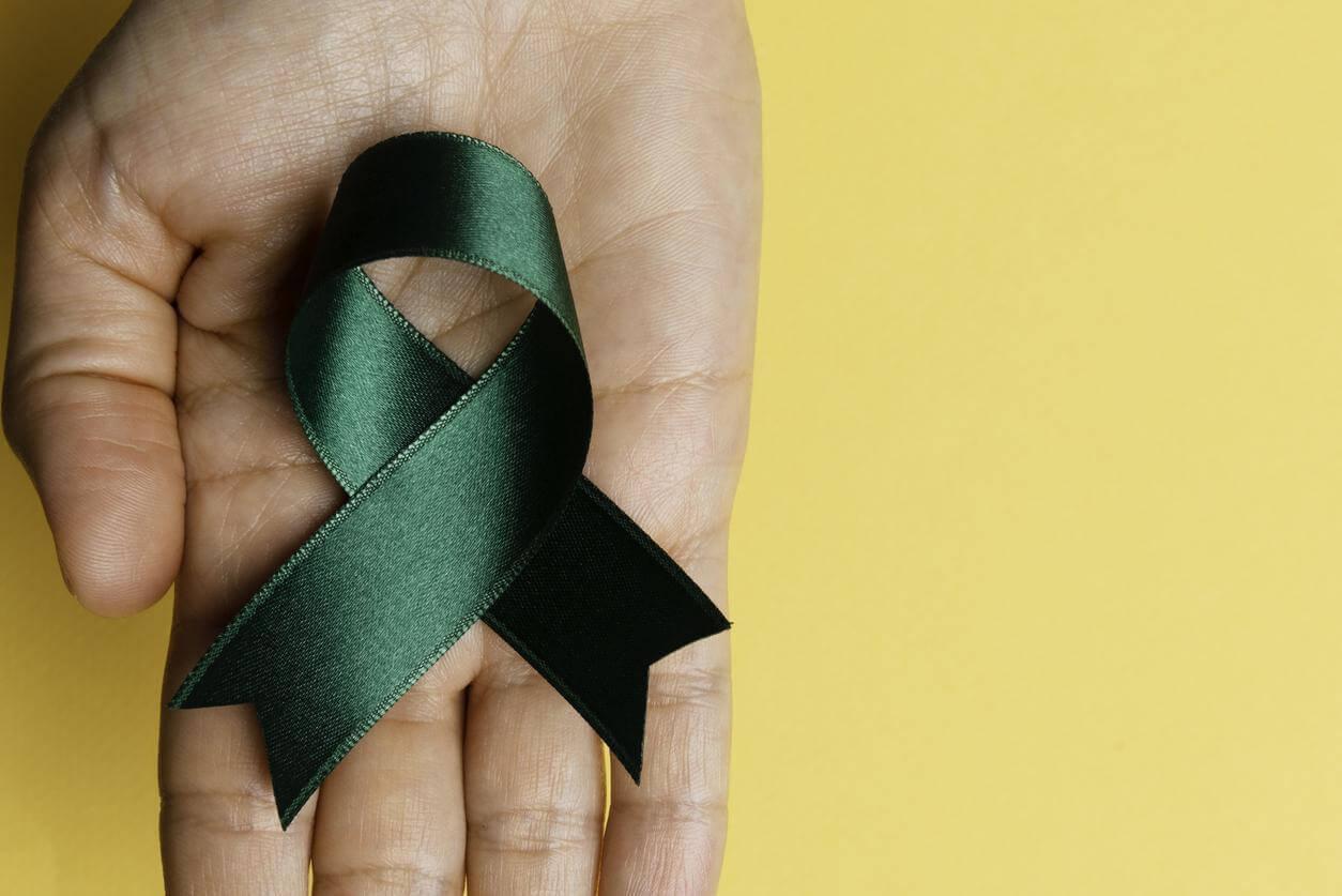 Hand holding green ribbon.