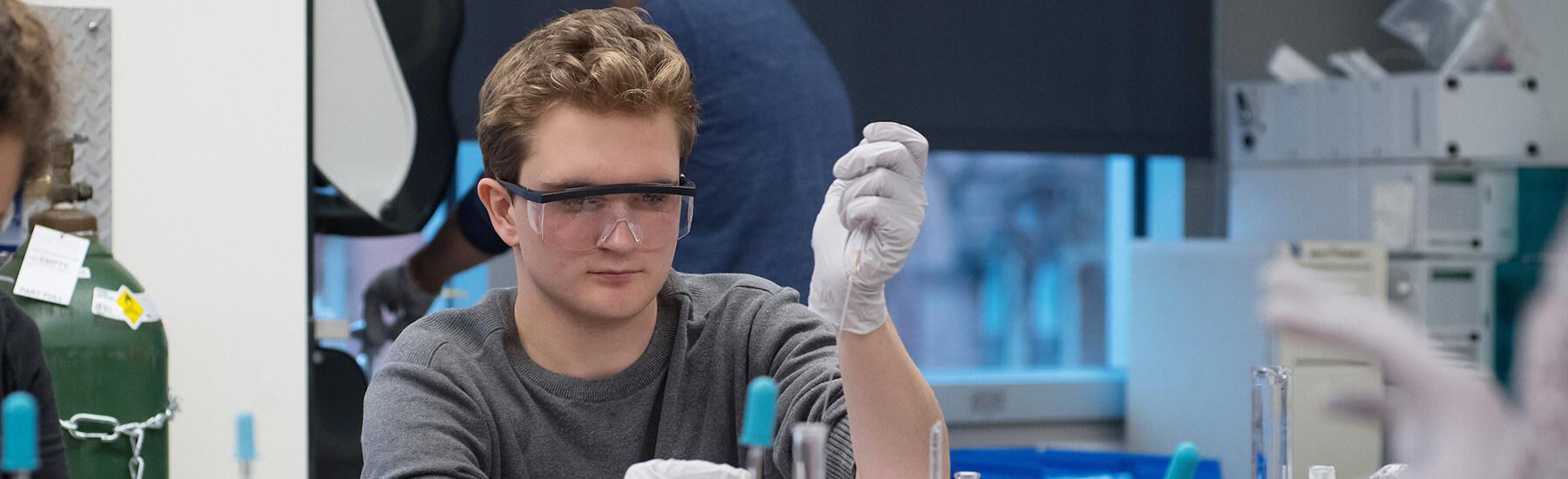 A person with glasses and gloves in a laboratory