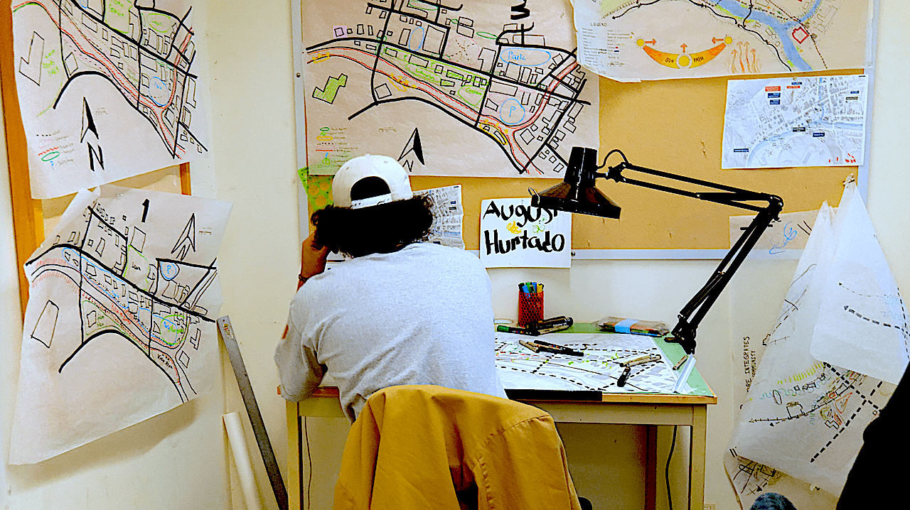 Student in a landscape design studio with drawings on the walls