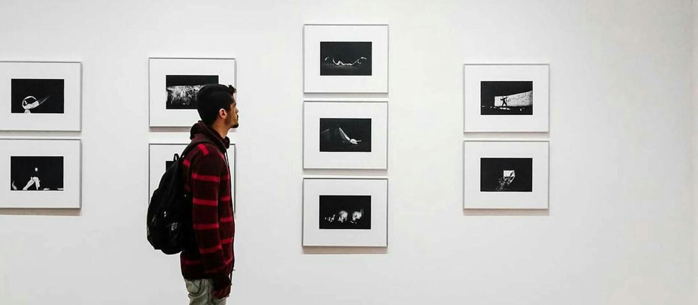 young man at an art show looking at photographs
