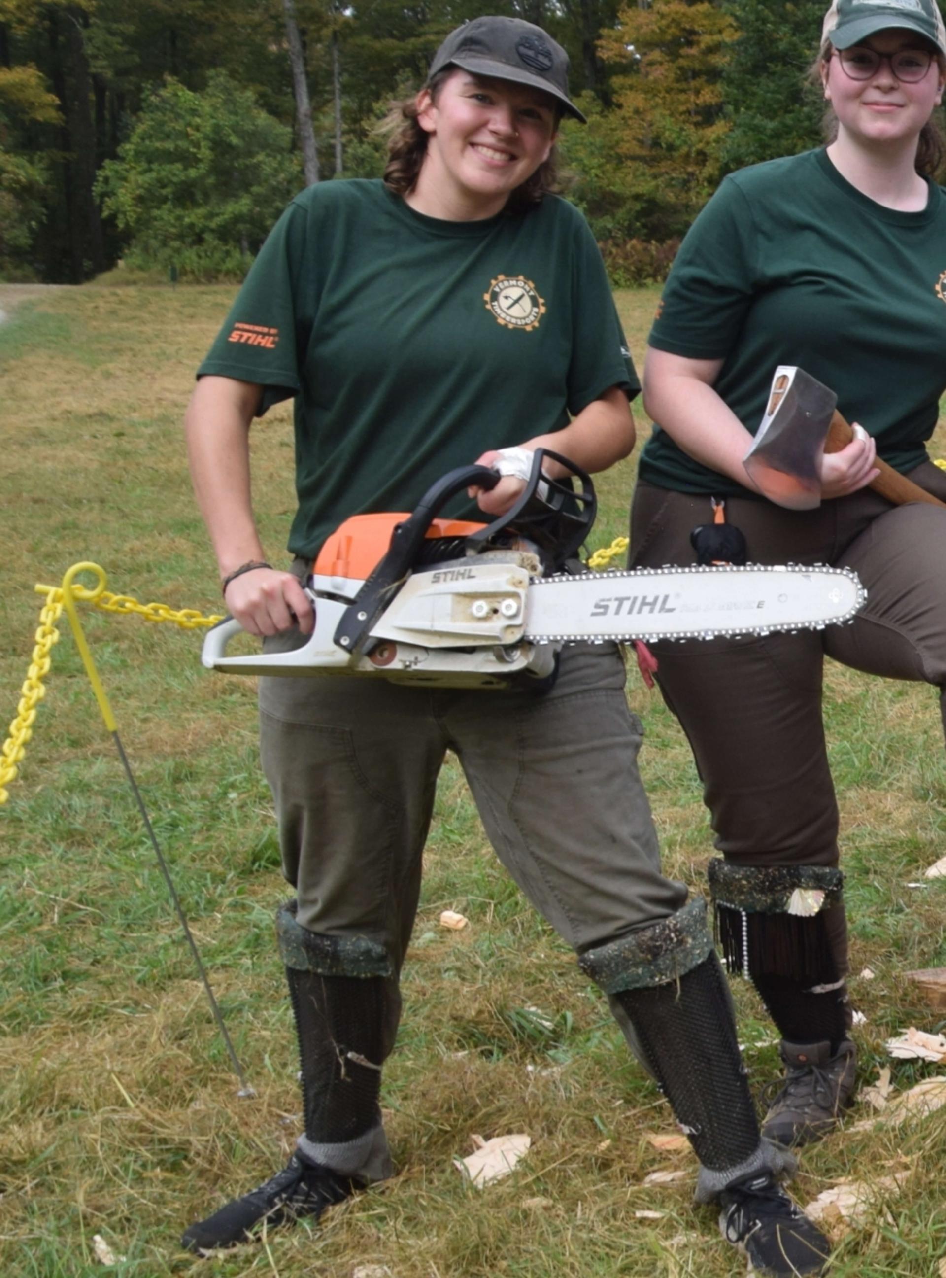 Es Sweeney holding a chainsaw and smiling with a Timbersports teammate.