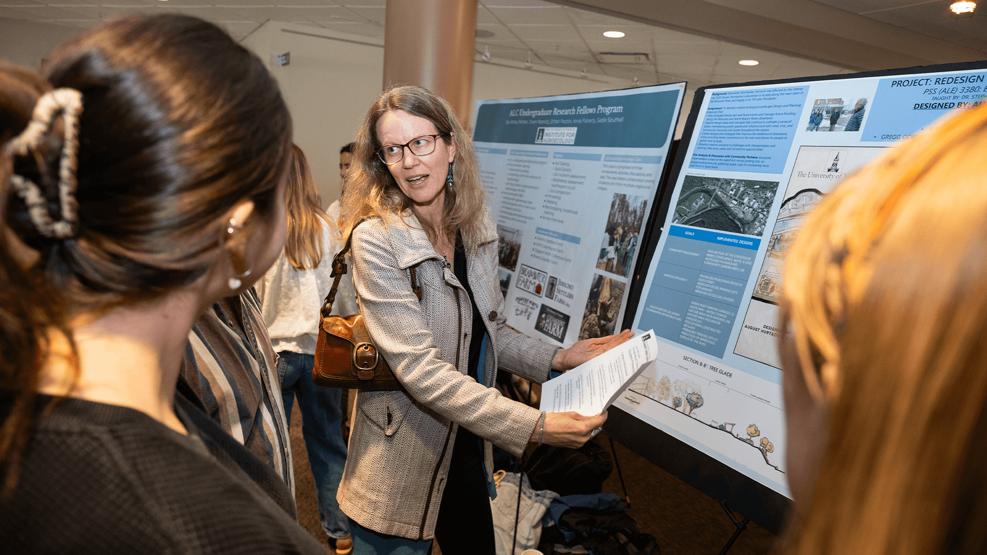 Woman presents a poster to a group at a showcase.