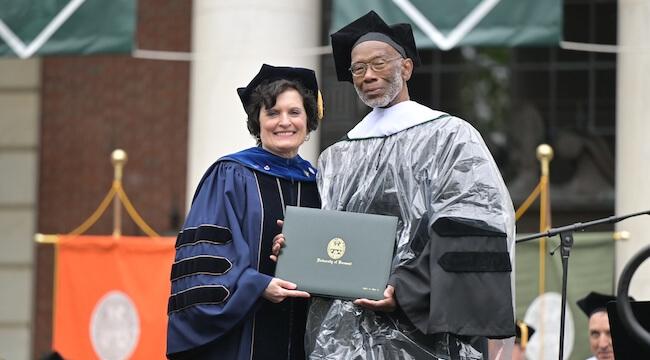man receiving diploma  from woman in regalia