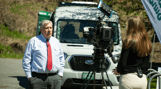 a man standing in front of a Cancer Center branded van being interviewed on camera