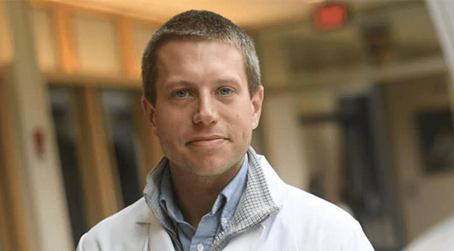 a man in a white coat smiling