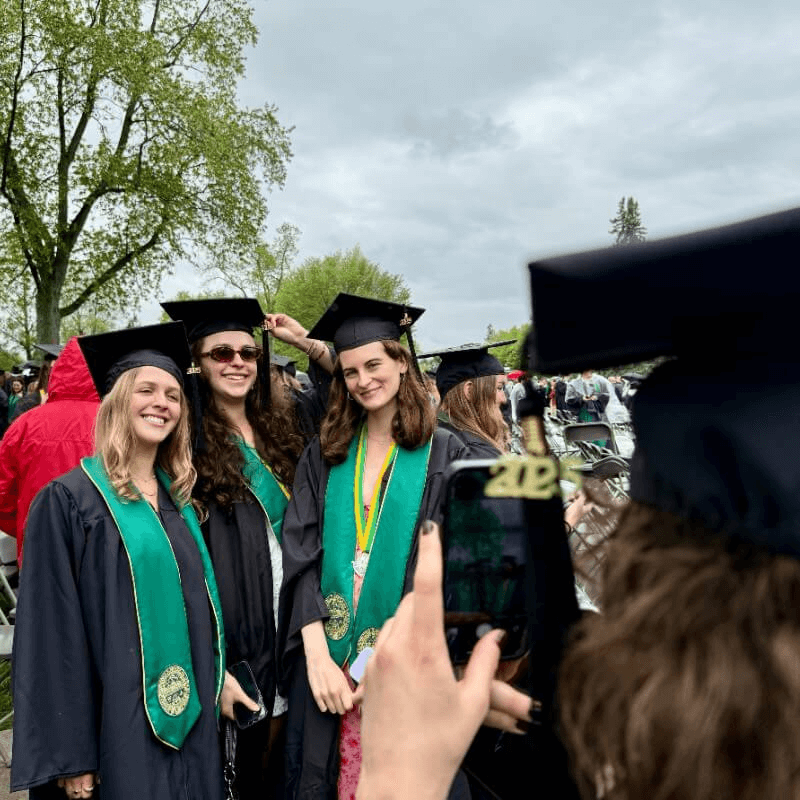 Three students having their photo taken at commencement