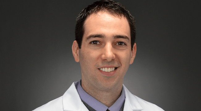 a man in a white coat smiling