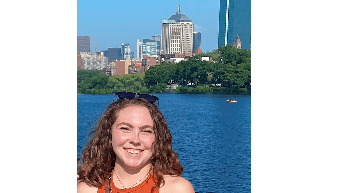 Elizabeth smiling with the museum across a waterway in the background