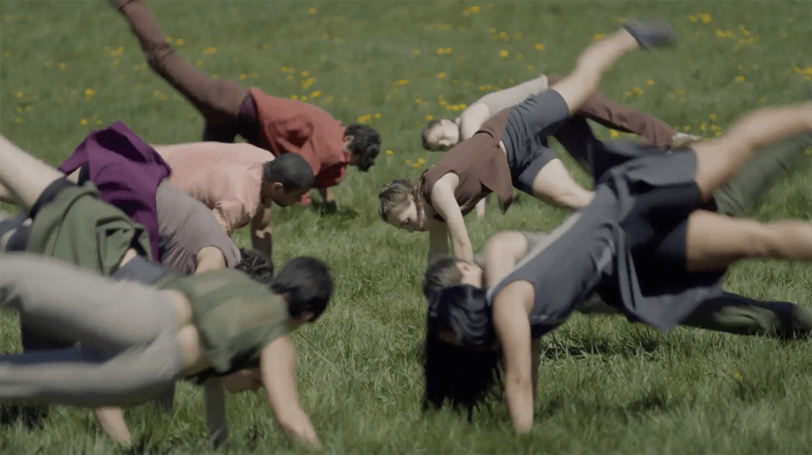 people in hand-stands in a circle on a grassy field