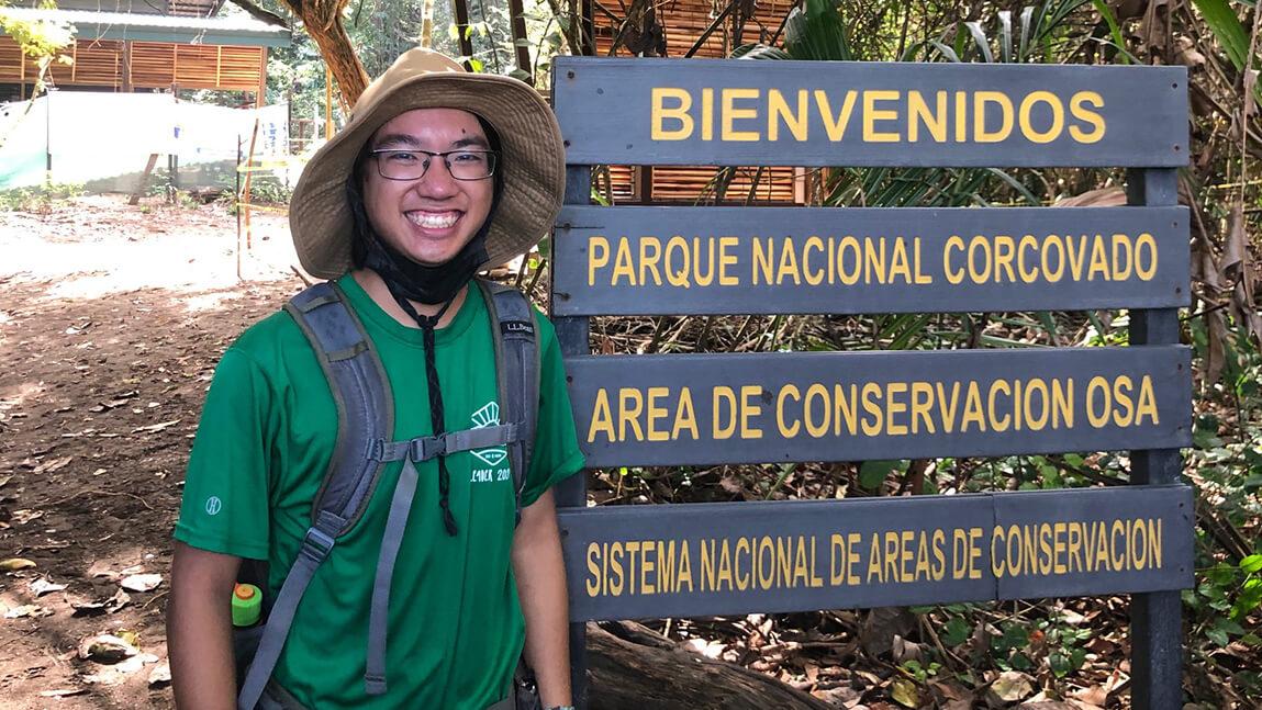 Jonah Stern stands next to wooden sign in Costa Rica.
