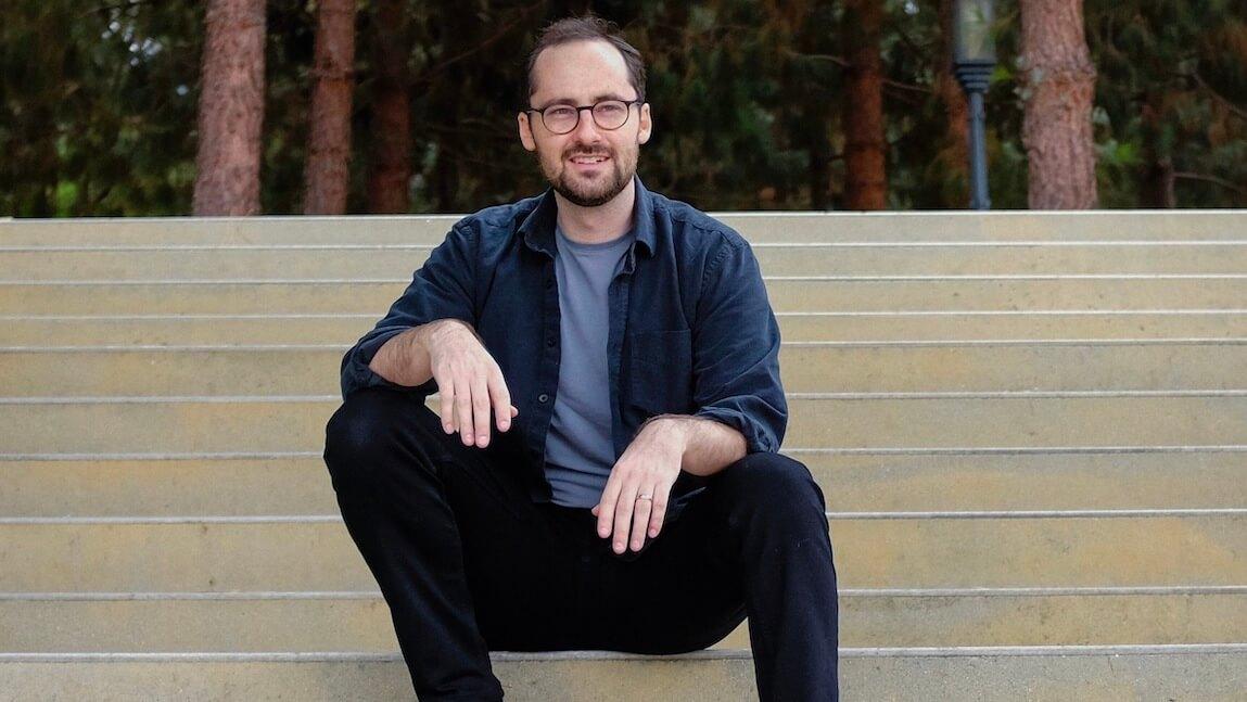 profile photo of CALS alum John Moses sitting on a large outdoor public staircase