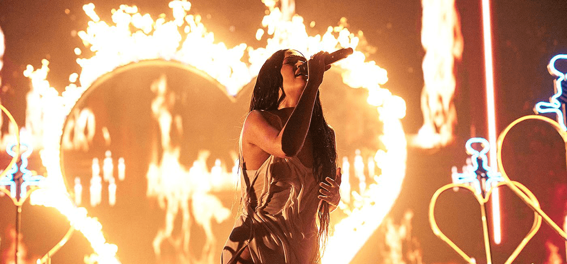 kacey musgraves on stage with fiery heart in background