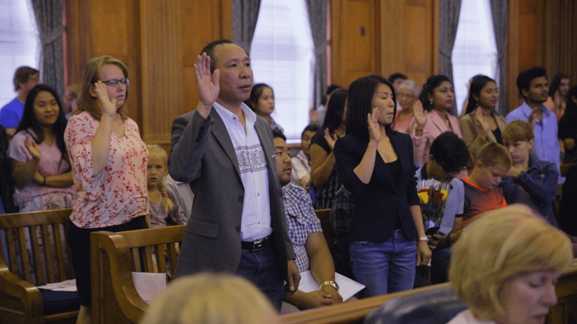 New Americans raising their hand as they take their oath