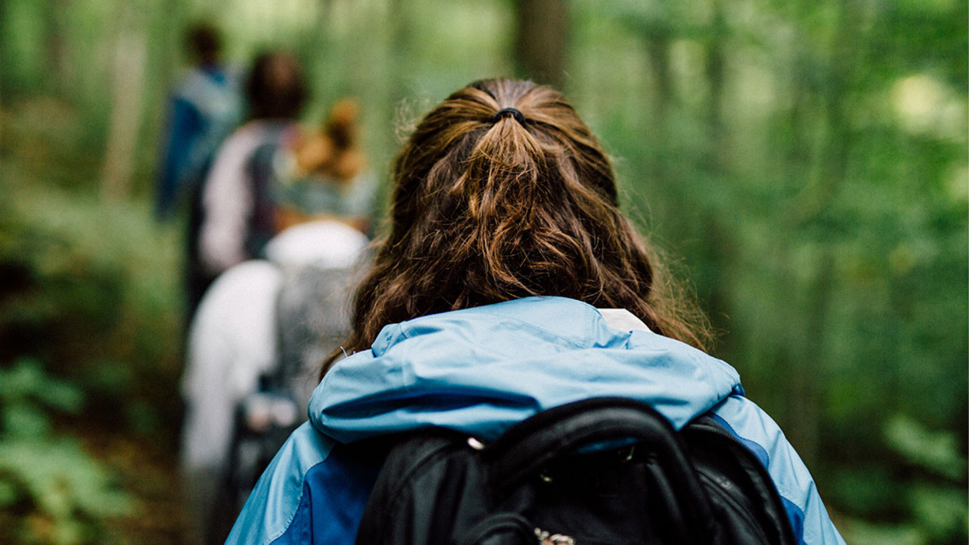 A photo of a woman walking through the forest. 