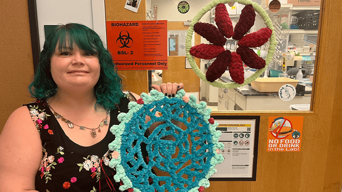 A woman posing with crocheted viruses