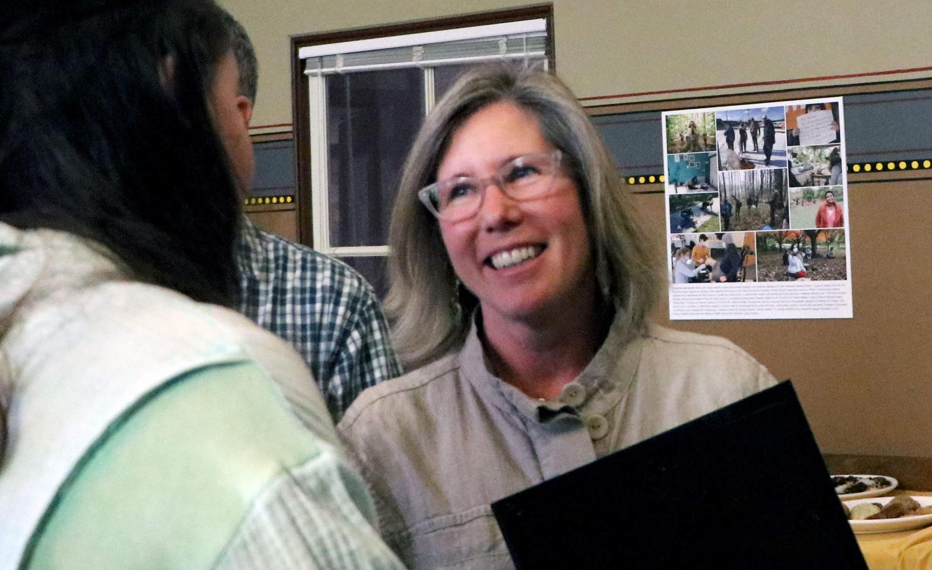 Cherie Morse is shown smiling while talking with a student. She is holding her award casually in her hand.