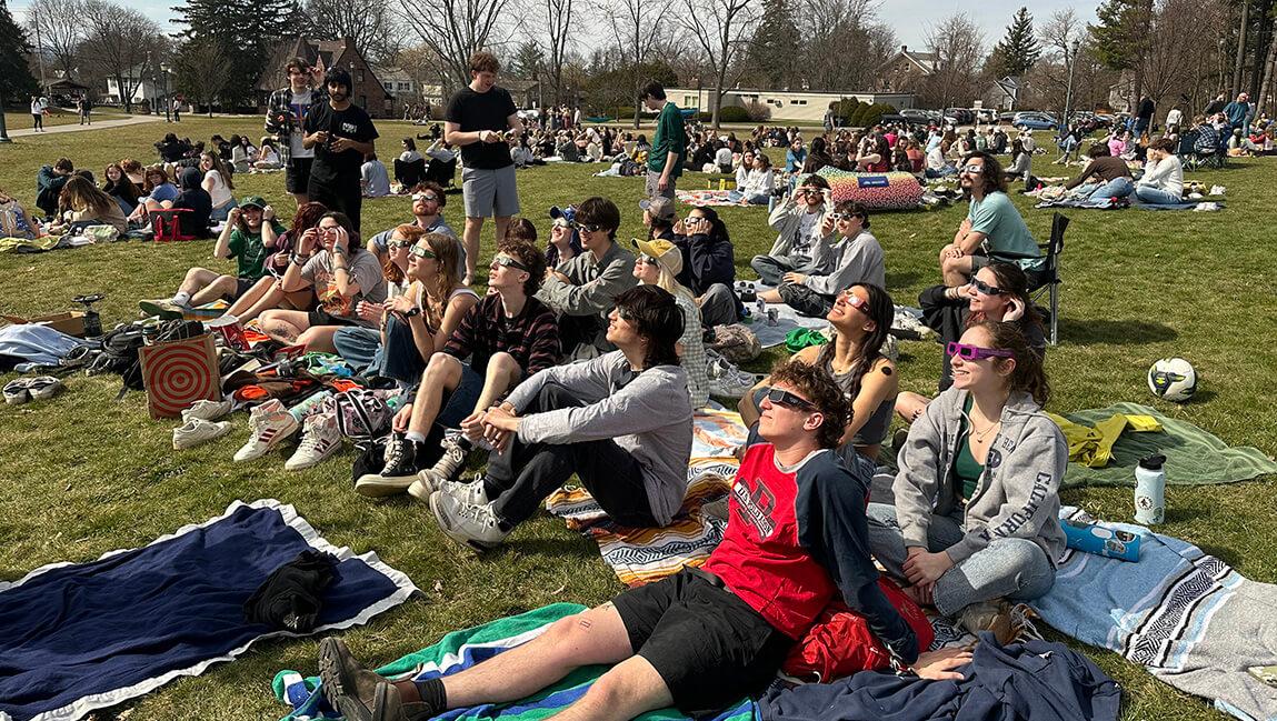 large group of students watching the eclipse on campus