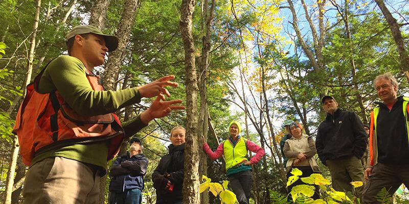 Ethan Tapper speaks to group of people in a forest.