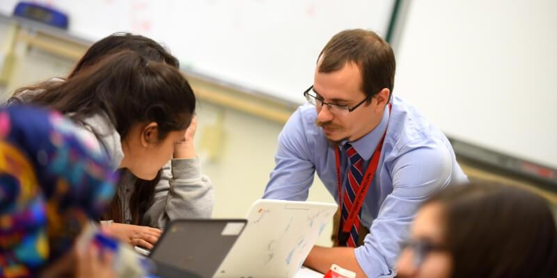 Tom Payeur instructs a student while using a laptop