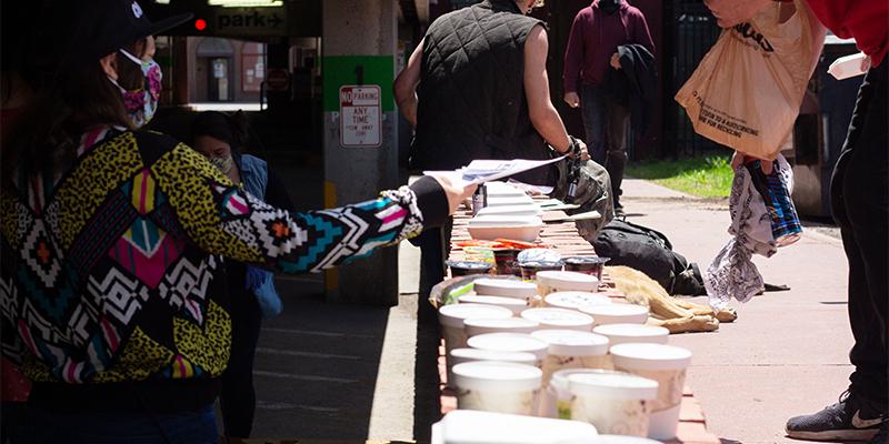 Meals in disposable containers lined up along a brick ledge.