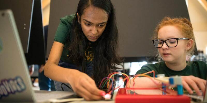 UVM student helping you student on computer