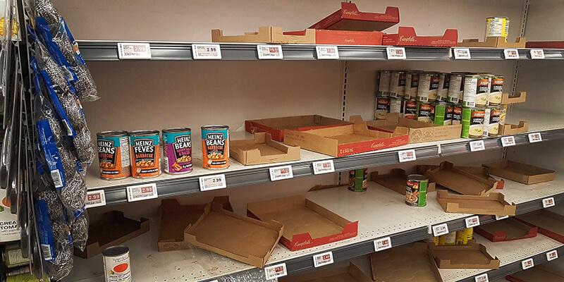 Empty grocery shelf with a few cans of beans