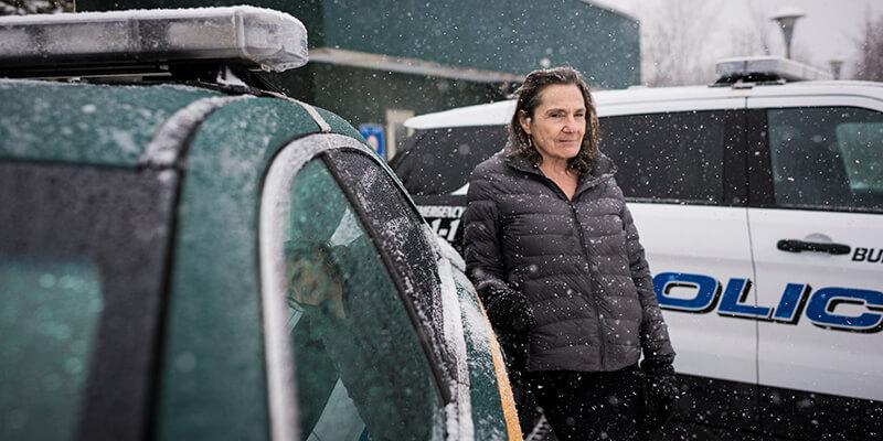 Stephanie Seguino outside a police car in snow