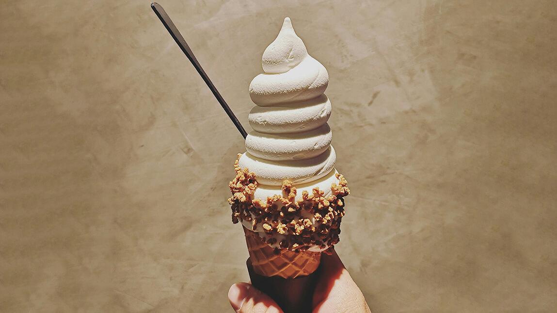 a soft-serve ice cream cone being held by a hand