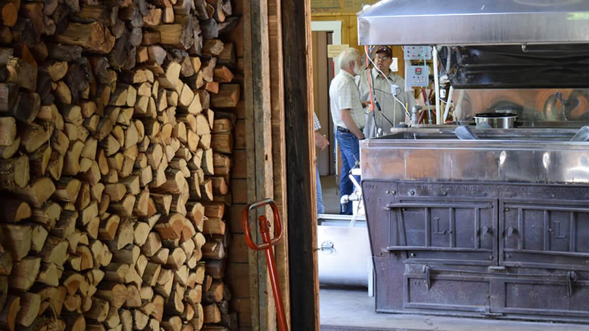 inside a sugarhouse, split wood on the left, evaporator on the right